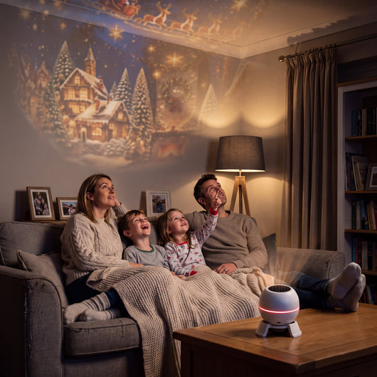 Family on a sofa looking up at a Christmas scene projected on the wall and ceiling