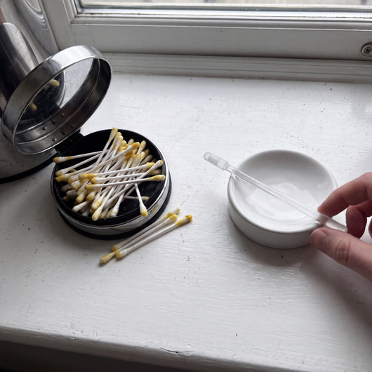 A bin of used cotton buds next to one clear reusable swab