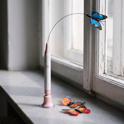 The Butterfly Flutter Cat Toy standing on a windowsill with two spare butterflies