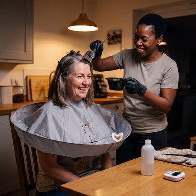 Hair colour applied at home with the cutting cape catching the drips