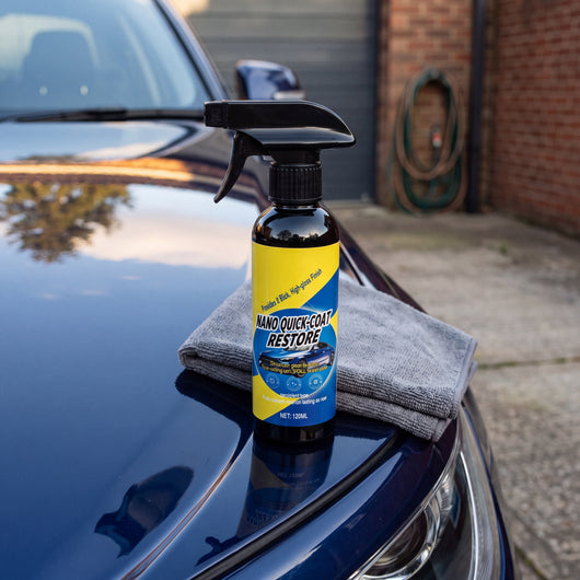Novum Car Nano Coat Spray bottle standing on the hood of a dark blue car beside a grey microfiber cloth