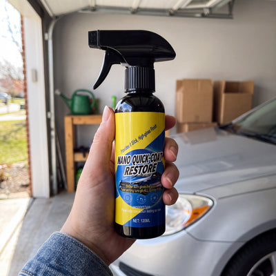 A hand holding the 120 ml Novum Car Nano Coat Spray bottle in a garage in front of a silver car