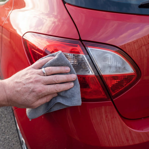 Wiping a car taillight with a microfiber cloth