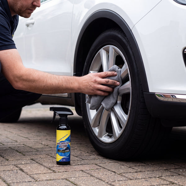 Wiping an alloy wheel with the spray bottle beside the tire