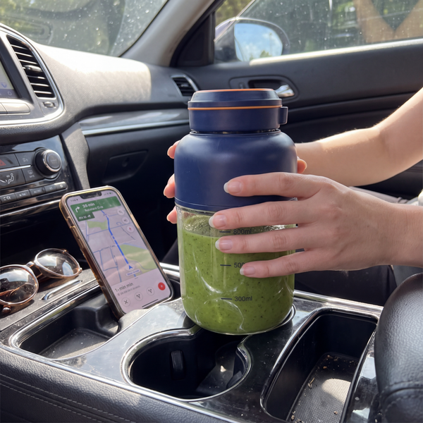 Novum Portable Juicer with a green smoothie in a car