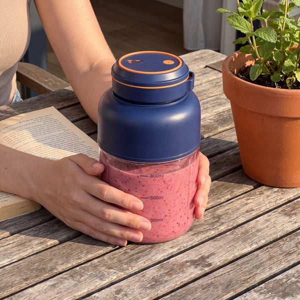 Novum Portable Juicer with a berry smoothie on a patio table