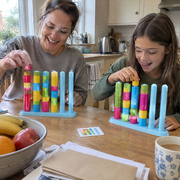 Mother and daughter racing on the Color Ring Stack Race Game at a kitchen table