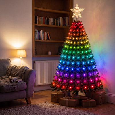 Novum Smart Christmas Tree Lights on a tree in a living room, colour bands from red to purple with a lit star topper