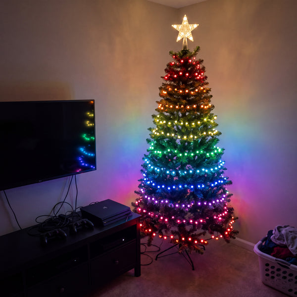 Multicolour tree lights on a Christmas tree beside a television unit