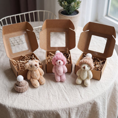 Novum Worry Bear in Brown, Pink and White beside their kraft gift boxes