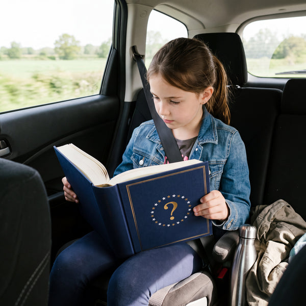 A girl reads the encyclopedia in the back seat of the car on a road trip
